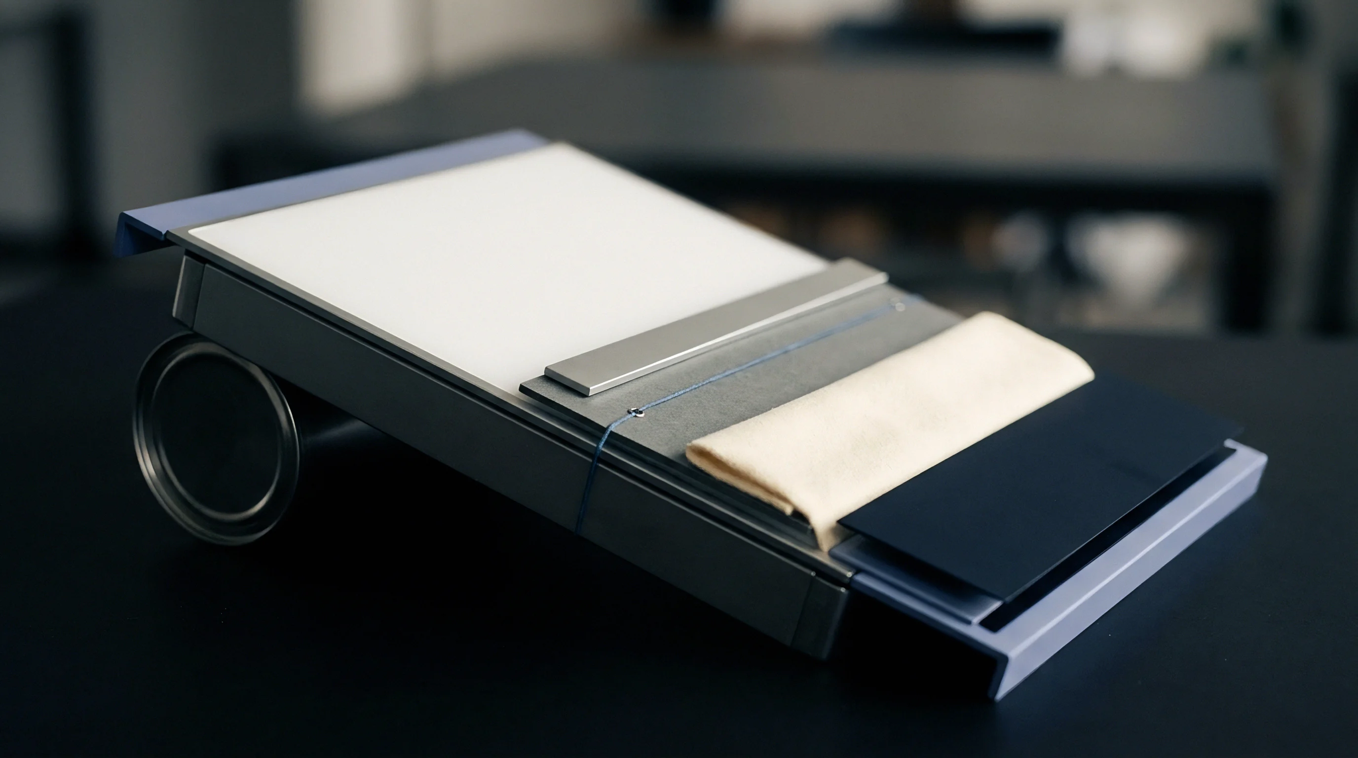 An inclined material board presents synthetic sheets, a steel bar, blue string, and a folded cream woven fabric sample.
